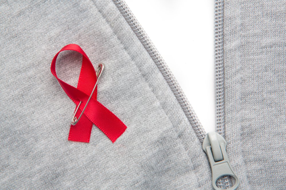 Aids awareness ribbon pinned on to grey zip jumper on white background