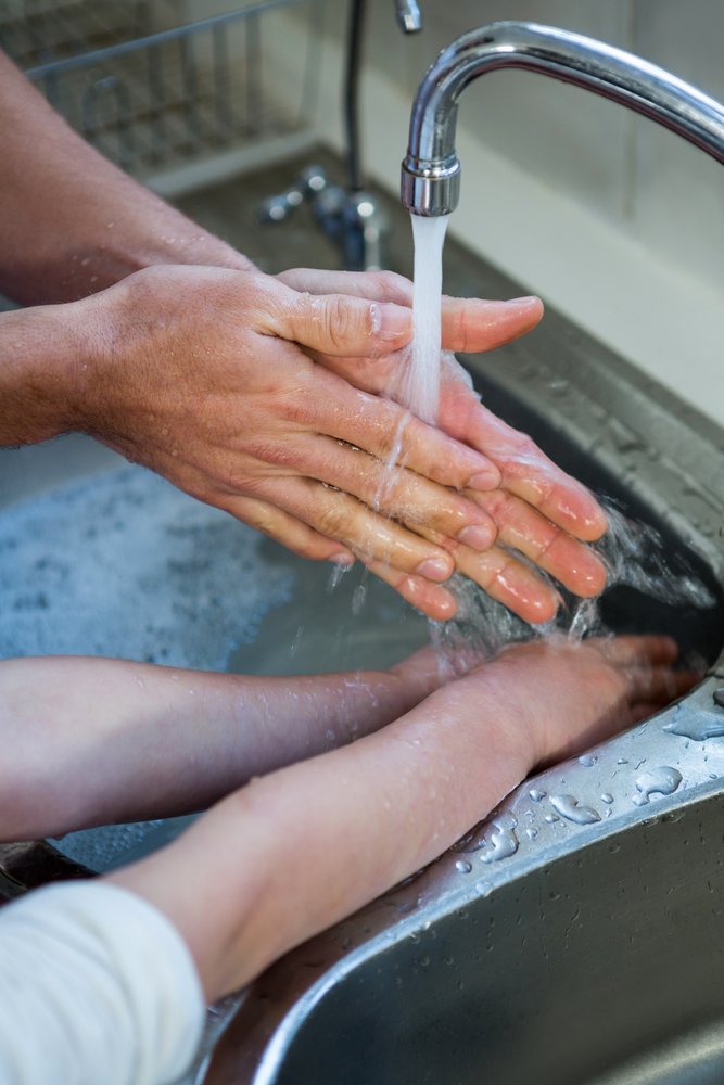 Father and son washing hands in the kitchen sink