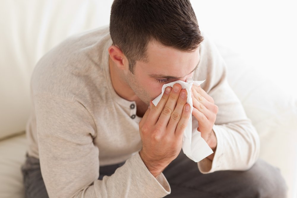 Ill man blowing his nose in his living room