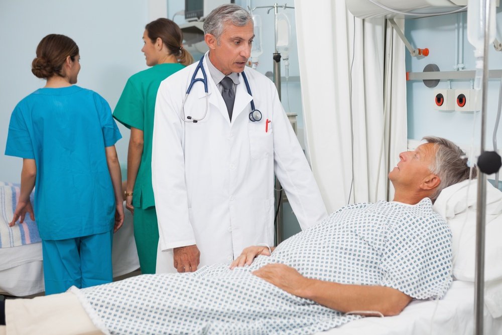 Patient lying in bed in hospital room talking to doctor