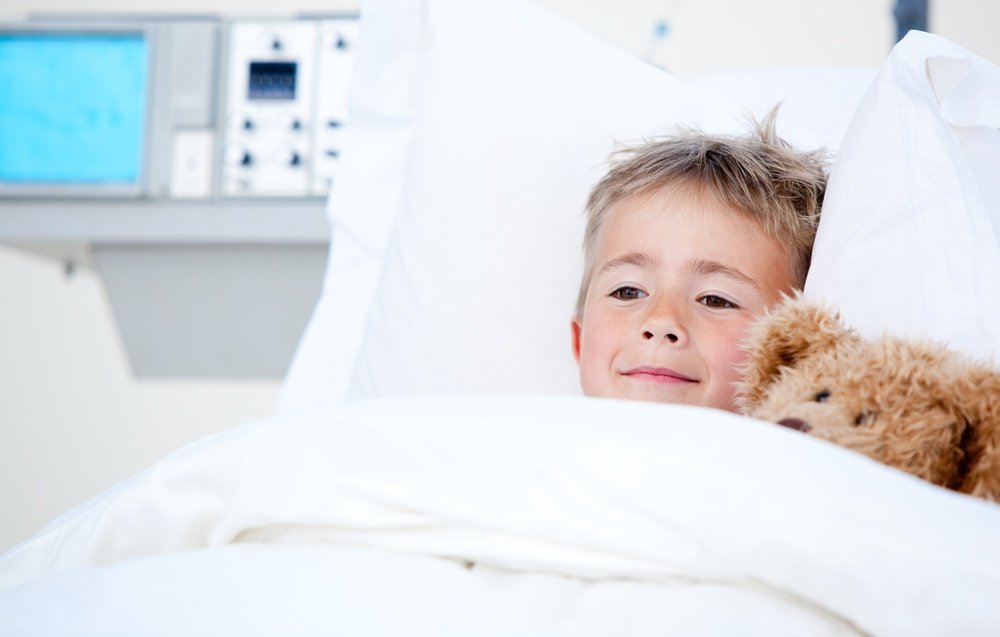 Portrait of a sick cute little boy lying in a hospital bed